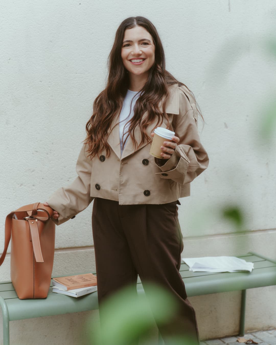 Guada con un café en la mano, sonriendo junto a un banco