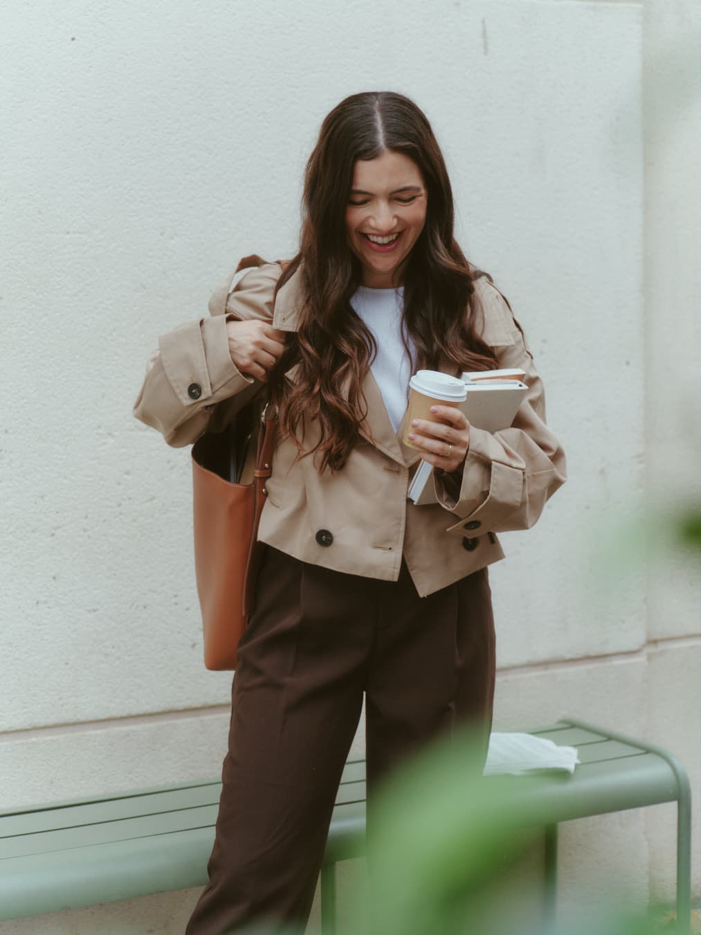 Guada riendo con un café y libros en la mano