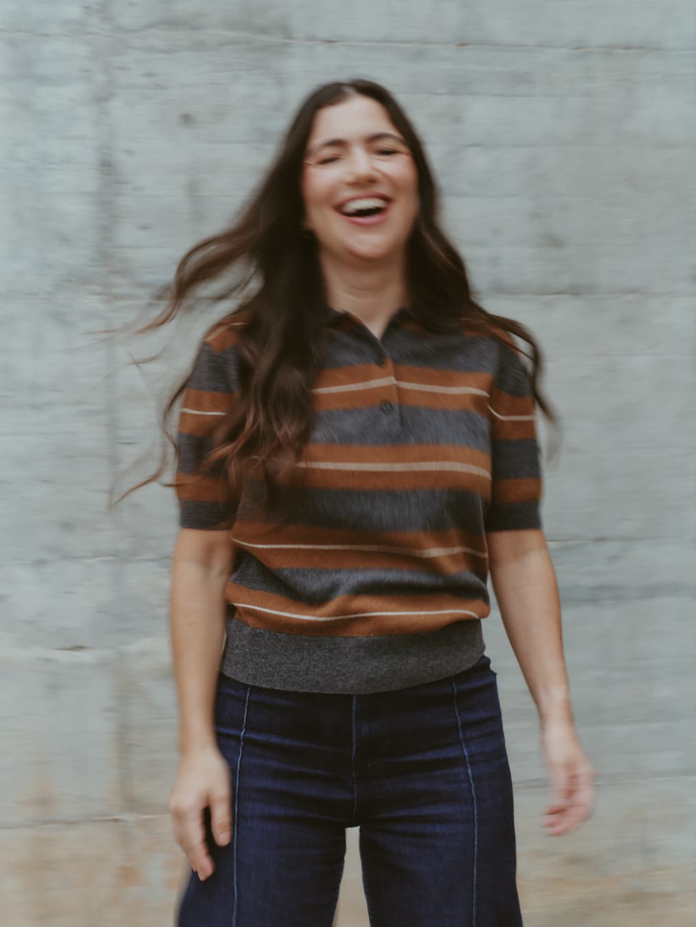 Guada riendo frente a una pared de hormigón, con el pelo en movimiento